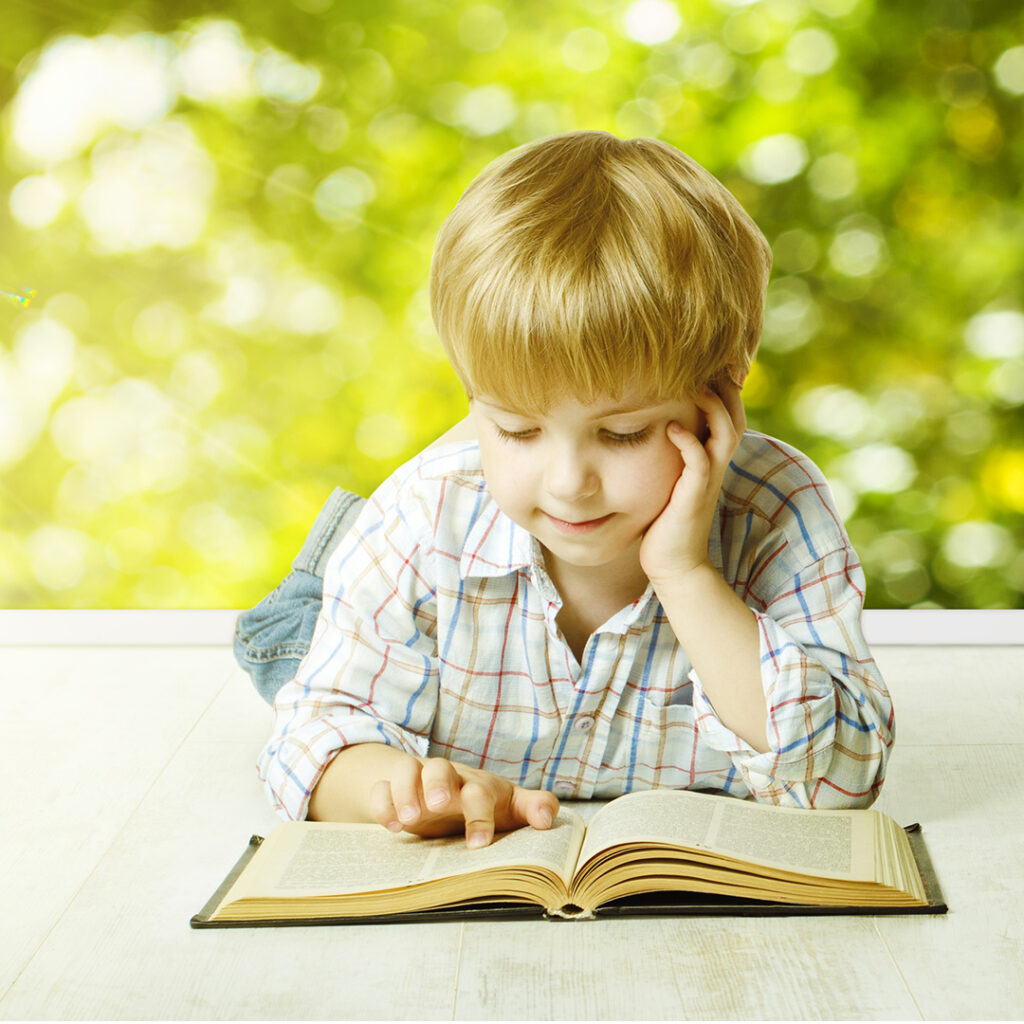 image of a young boy laying on his stomach reading a book